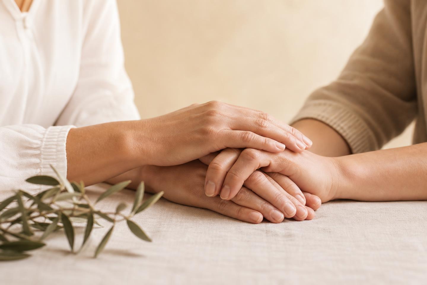 A reassuring hand resting over another woman's hands during a supportive conversation