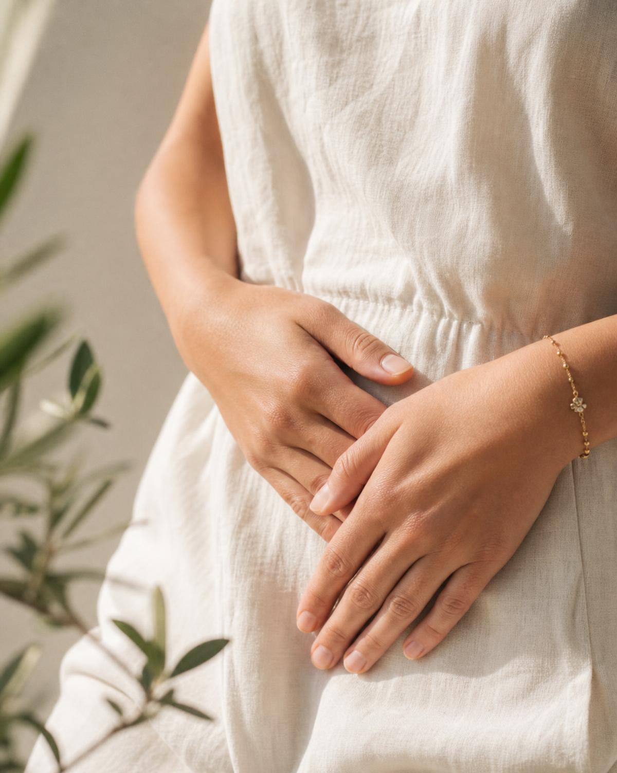 Woman's hands resting gently on her lower abdomen in a warm, calming gesture
