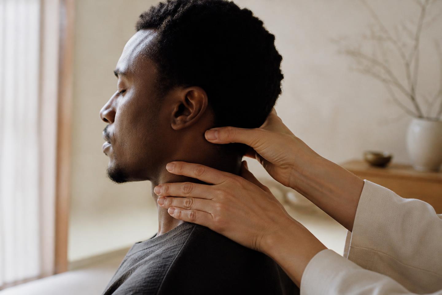 Close-up of a physiotherapist's hands treating a patient's neck