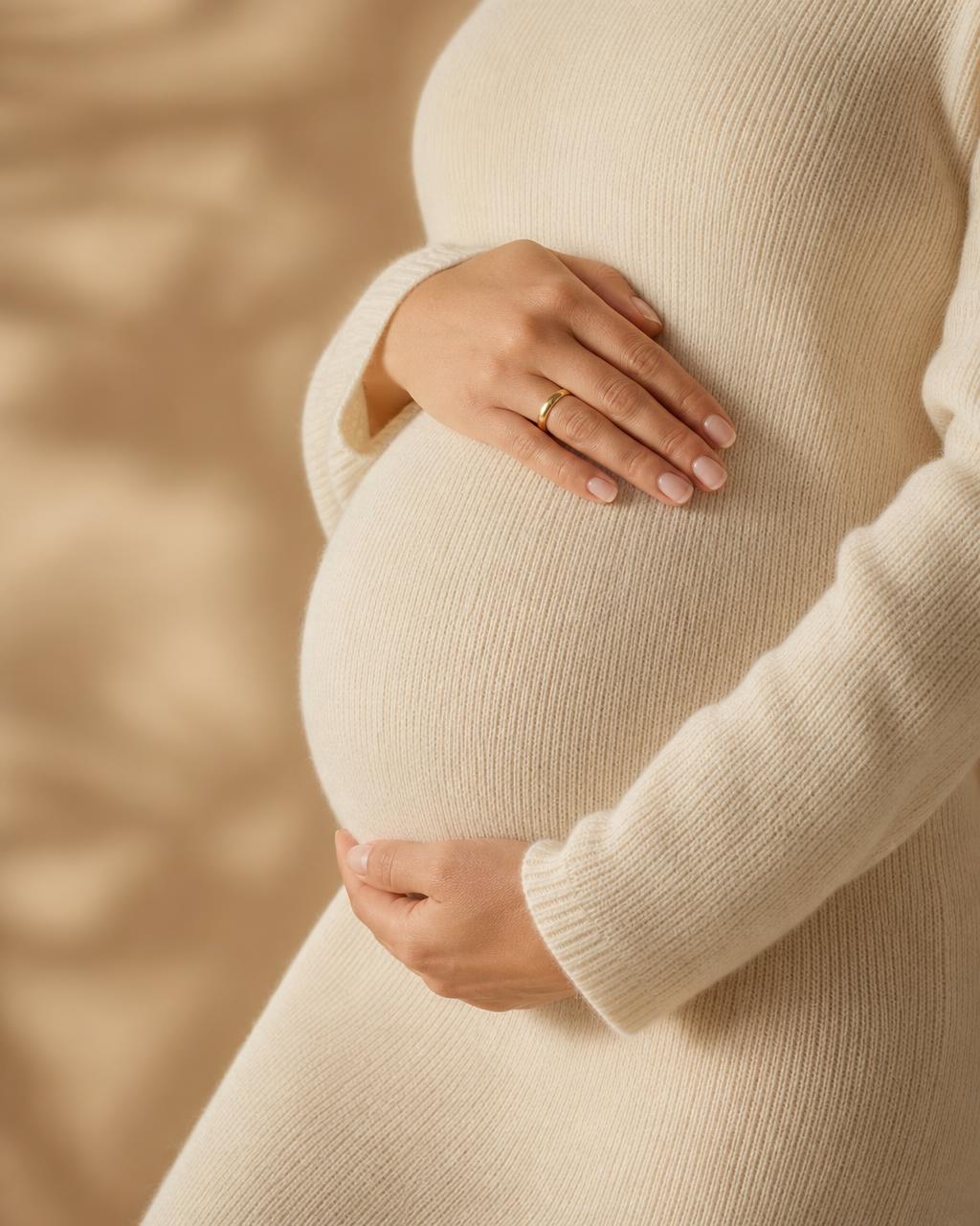 Pregnant woman's hands resting gently on her bump in soft natural light